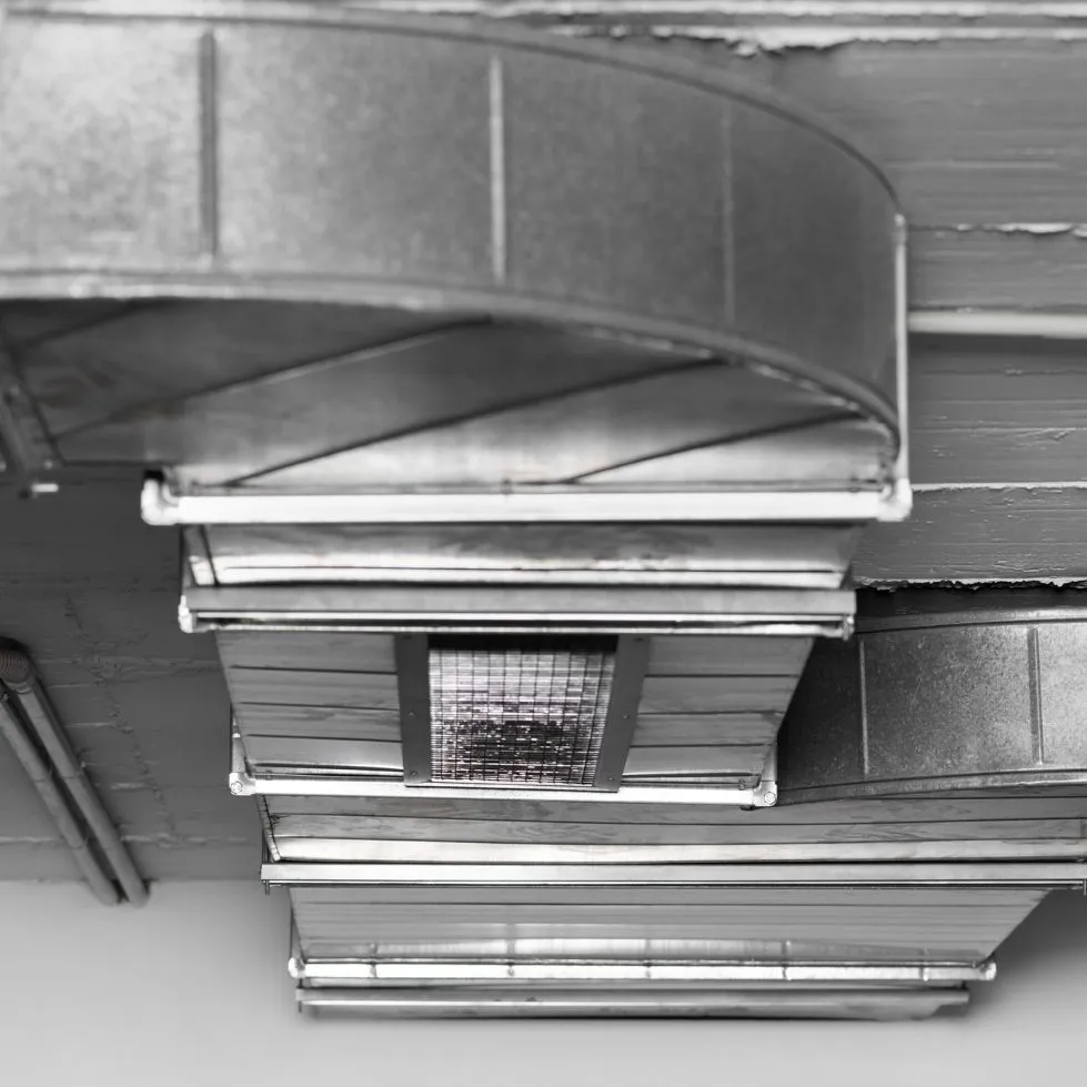 Black-and-white ceiling vents and ducts with a central air grille indoors
