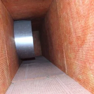Inside a brick-lined duct, a large metal cylinder sits at the far end